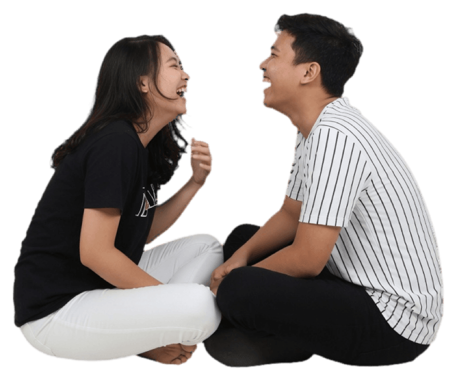 A couple sitting cross-legged on the floor, laughing together